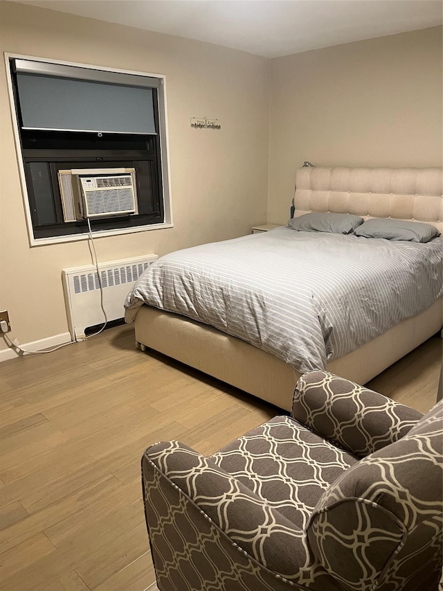 bedroom featuring cooling unit, light wood-type flooring, and radiator heating unit