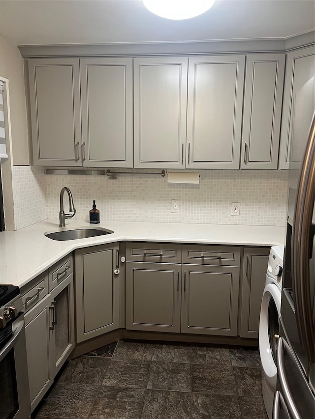 kitchen featuring backsplash, gray cabinets, sink, and washer / dryer