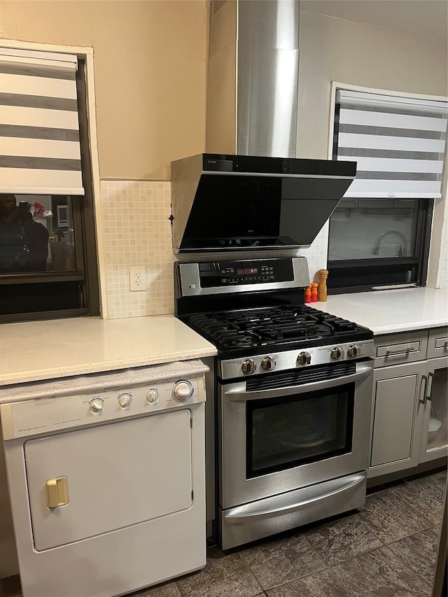 kitchen with wall chimney exhaust hood, gray cabinets, dishwasher, and stainless steel range with gas cooktop