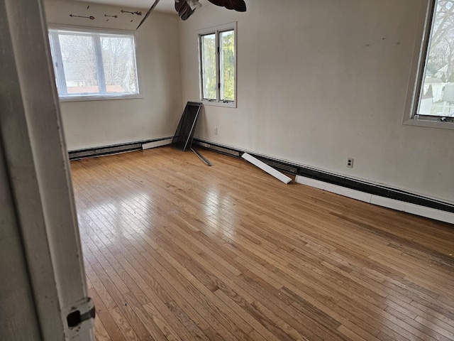 spare room featuring ceiling fan, light wood-type flooring, and baseboard heating