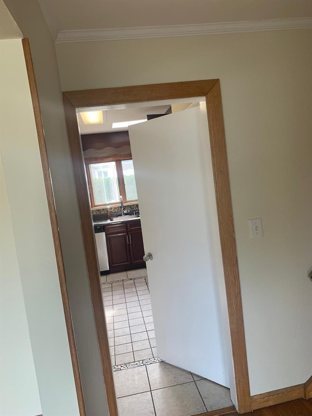 hallway with sink, light tile patterned floors, and ornamental molding