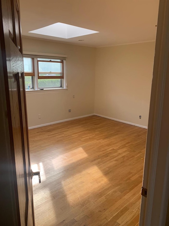 unfurnished room featuring light hardwood / wood-style floors and a skylight