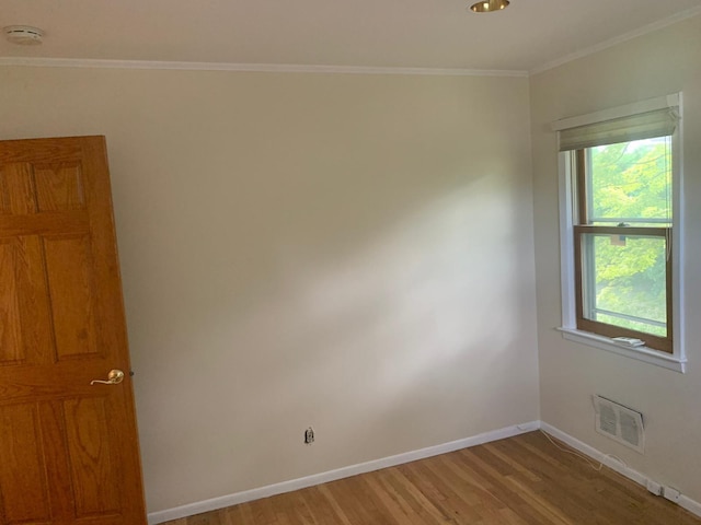 empty room with a wealth of natural light, crown molding, and light hardwood / wood-style floors