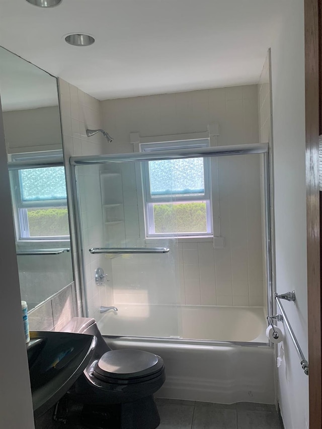 full bathroom featuring sink, a wealth of natural light, bath / shower combo with glass door, and tile patterned floors