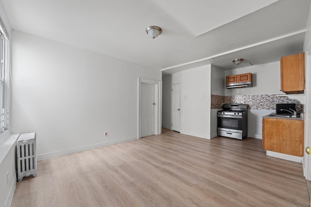 kitchen featuring stainless steel range oven, light wood-type flooring, and radiator