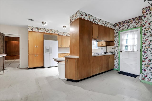 kitchen with kitchen peninsula and white fridge with ice dispenser