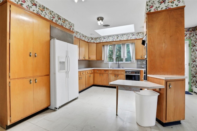 kitchen featuring wall oven, white fridge with ice dispenser, and sink