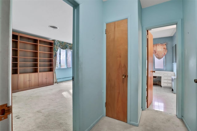 corridor with light carpet and a baseboard heating unit