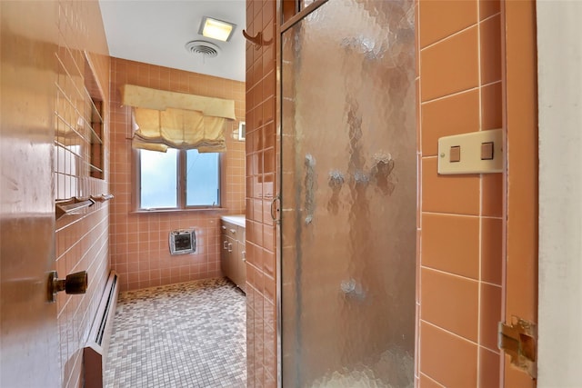 bathroom with tile patterned floors, heating unit, tile walls, and walk in shower