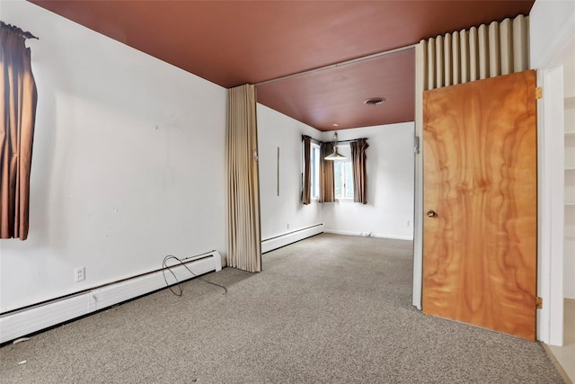 spare room with carpet floors and a baseboard heating unit