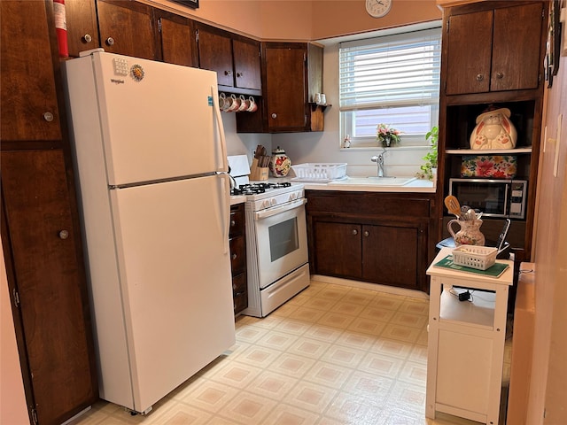 kitchen with dark brown cabinets, sink, and white appliances