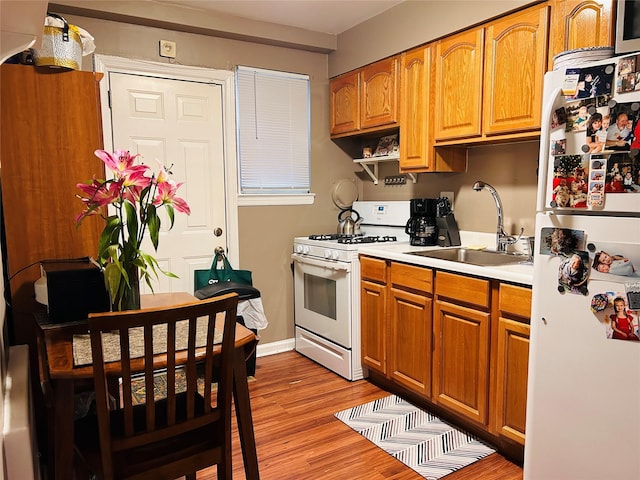 kitchen with white appliances, sink, and light wood-type flooring