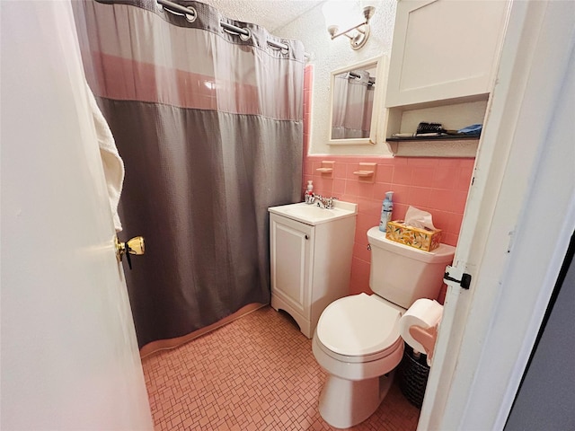 bathroom with vanity, toilet, and tile walls