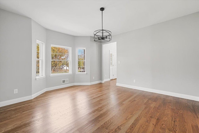 unfurnished dining area featuring hardwood / wood-style floors and a notable chandelier