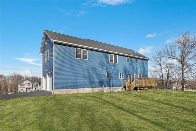 rear view of house with a wooden deck, a yard, and a garage