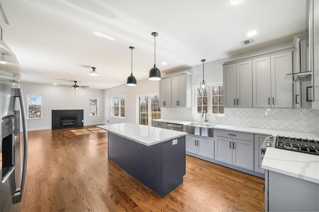 kitchen with decorative light fixtures, gray cabinets, light stone countertops, and tasteful backsplash