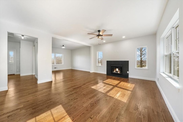 unfurnished living room with a fireplace, dark hardwood / wood-style floors, and ceiling fan