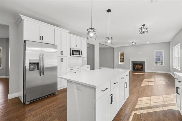 kitchen with white cabinetry, a center island, pendant lighting, appliances with stainless steel finishes, and hardwood / wood-style flooring