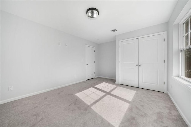 unfurnished bedroom with a closet and light colored carpet