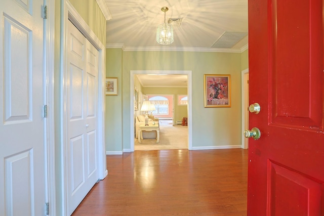 entryway featuring hardwood / wood-style floors, ornamental molding, and an inviting chandelier