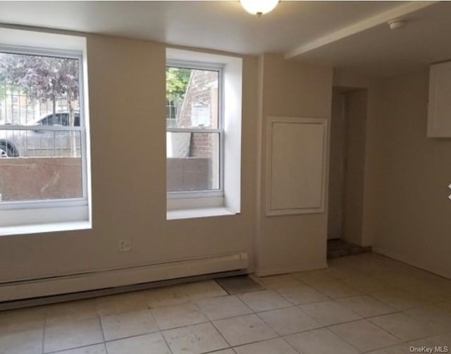 unfurnished room with light tile patterned floors and a baseboard radiator