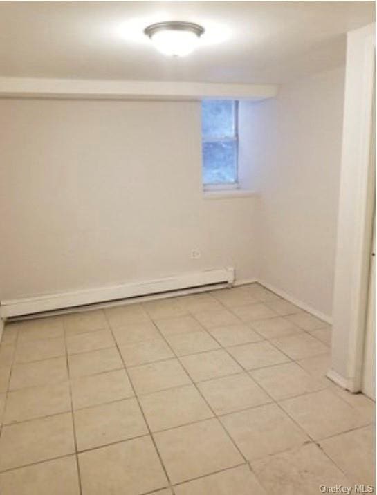 tiled empty room with a baseboard heating unit