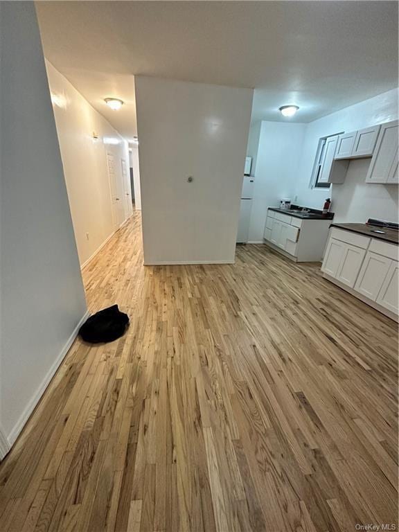 kitchen with white cabinets, light wood-type flooring, and white fridge