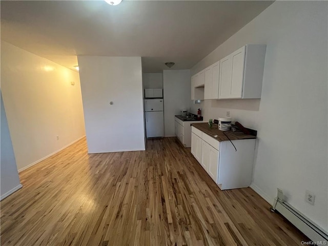 kitchen with white fridge, white cabinetry, light hardwood / wood-style flooring, and a baseboard heating unit