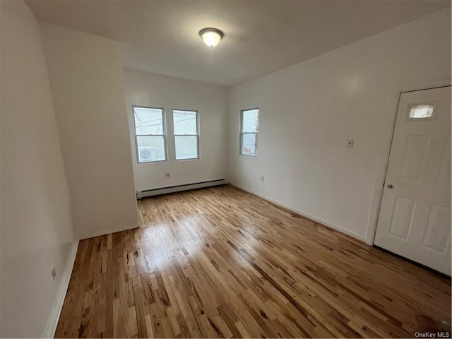 unfurnished room featuring light wood-type flooring and a baseboard heating unit