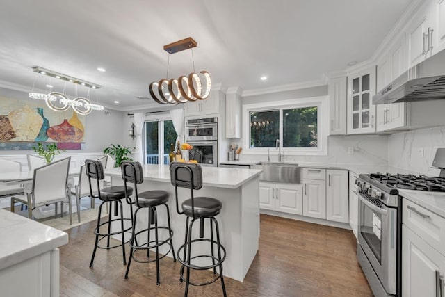 kitchen featuring decorative light fixtures, a center island, sink, appliances with stainless steel finishes, and white cabinets