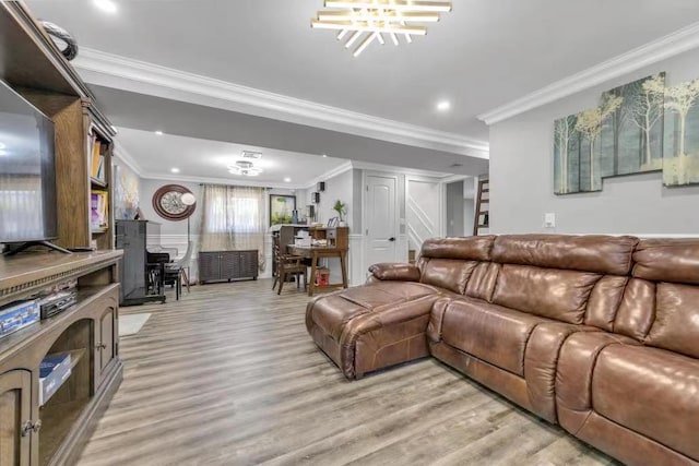 living room with light wood-type flooring, a notable chandelier, and ornamental molding