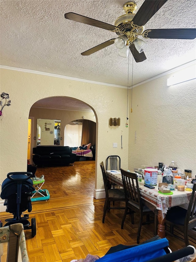 dining space featuring a textured ceiling, ceiling fan, parquet floors, and crown molding