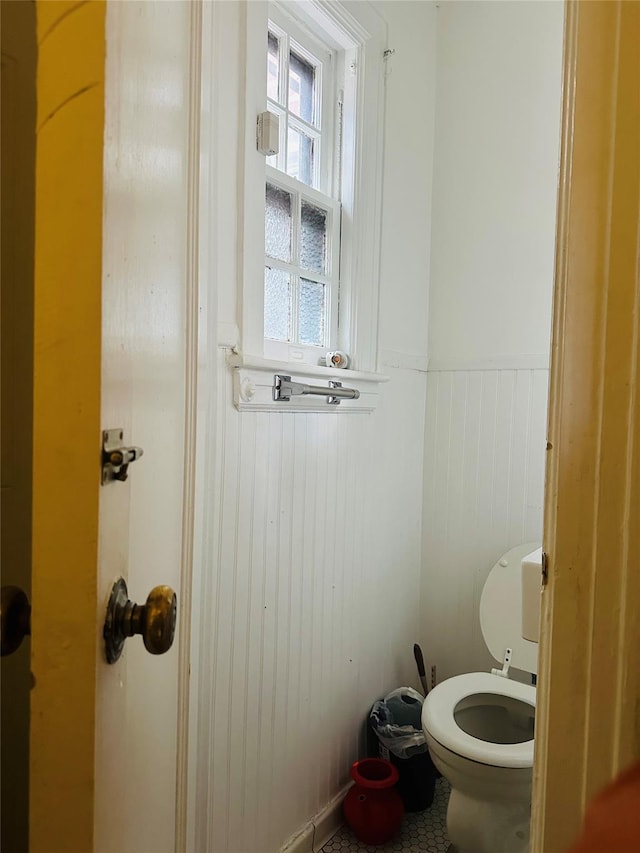 bathroom featuring wooden walls and toilet