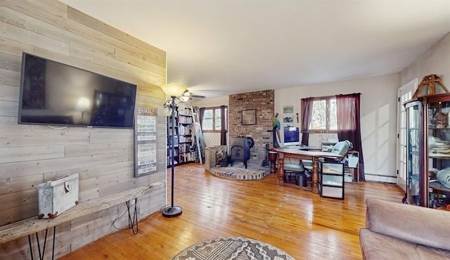 living room with a wood stove, wood walls, wood-type flooring, and a baseboard heating unit