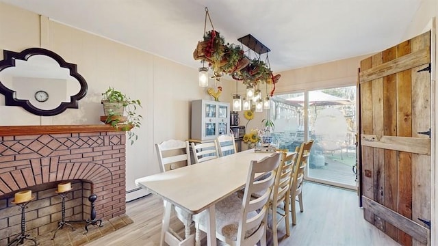 dining room featuring light wood-type flooring, wooden walls, and a baseboard heating unit