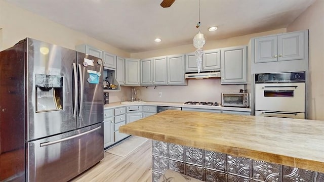 kitchen featuring gray cabinetry, sink, light wood-type flooring, appliances with stainless steel finishes, and decorative light fixtures