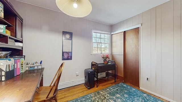 home office featuring hardwood / wood-style floors, ceiling fan, wooden walls, and a baseboard heating unit