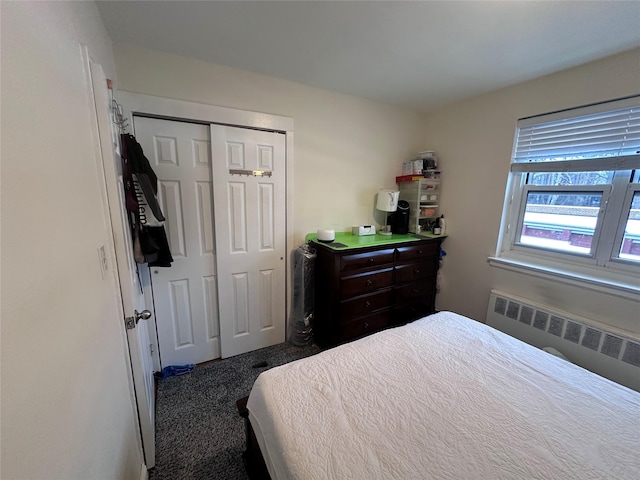 bedroom with dark carpet, radiator heating unit, and a closet