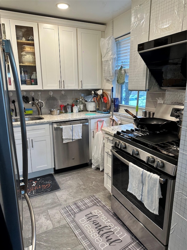 kitchen featuring extractor fan, appliances with stainless steel finishes, white cabinets, and light stone counters