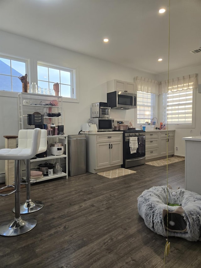 kitchen with white cabinets, stainless steel appliances, plenty of natural light, and hanging light fixtures