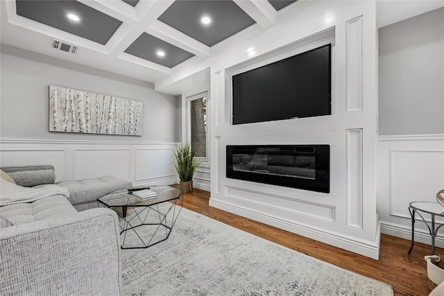 living room featuring beamed ceiling, ornamental molding, hardwood / wood-style flooring, and coffered ceiling