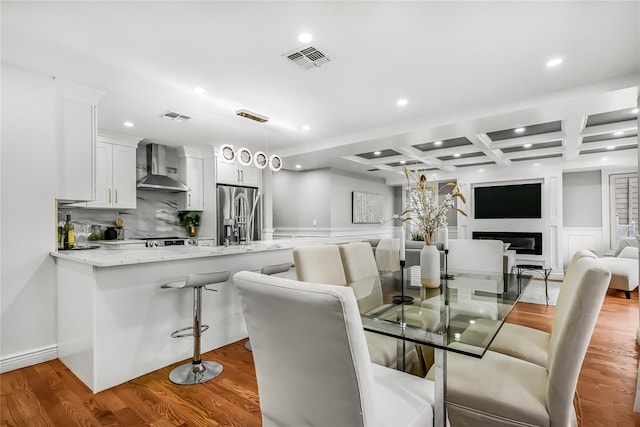 dining space with beam ceiling, light hardwood / wood-style flooring, and coffered ceiling