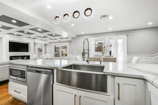 kitchen featuring sink, stainless steel appliances, coffered ceiling, light stone counters, and white cabinets