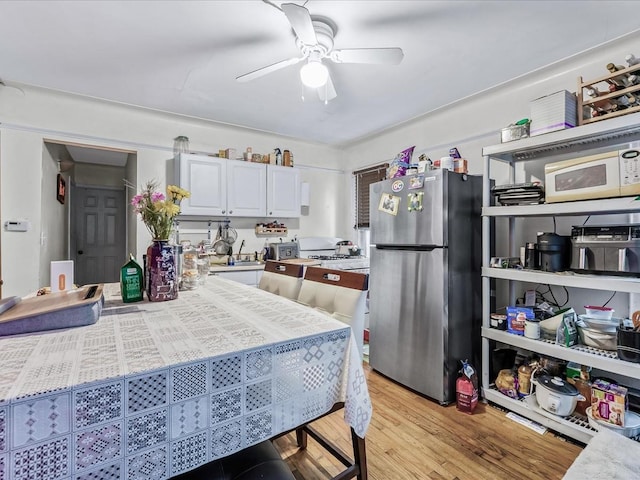 kitchen featuring light wood-type flooring, ceiling fan, stainless steel fridge, and white cabinetry