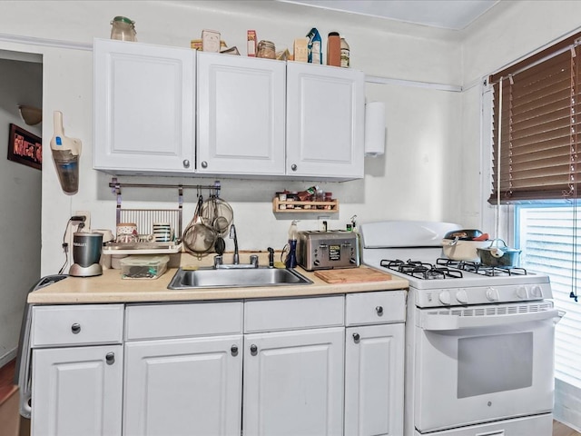 kitchen featuring sink, white cabinetry, and white gas stove