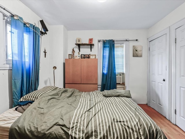 bedroom with cooling unit and wood-type flooring