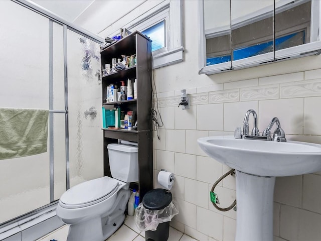 bathroom with sink, tile walls, a shower with shower door, toilet, and tile patterned floors