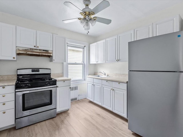 kitchen featuring stainless steel appliances, radiator heating unit, and white cabinetry