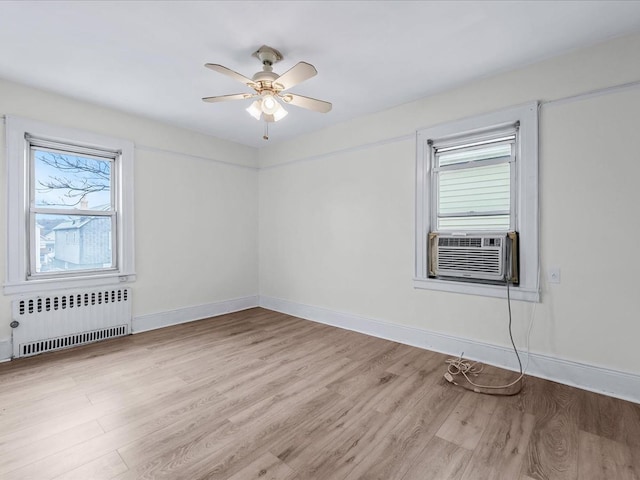 spare room featuring ceiling fan, light hardwood / wood-style flooring, radiator heating unit, and plenty of natural light