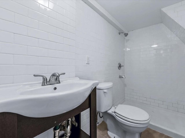 bathroom featuring a tile shower, toilet, and tile walls